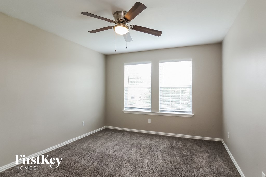 A room with a ceiling fan and carpeted floor.