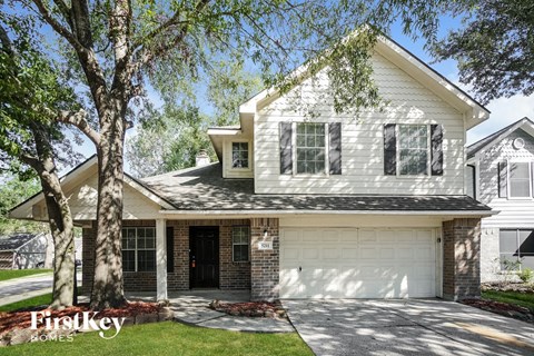 A house with a garage and a tree in front of it.