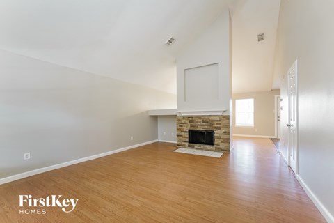 A spacious room with a fireplace and wooden flooring.