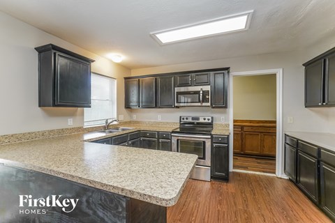 A kitchen with black cabinets and a granite countertop.
