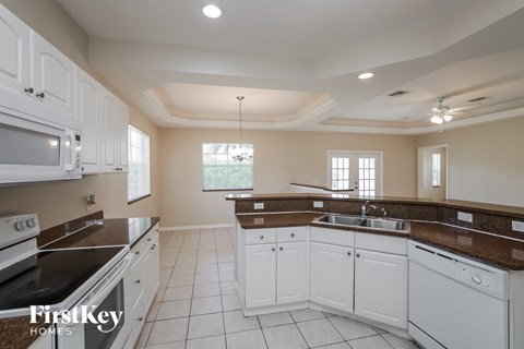 A kitchen with white cabinets and a black stove top oven.