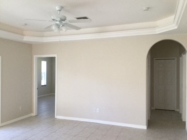 A room with a ceiling fan and tiled floor.