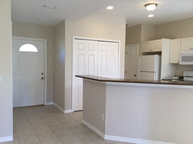 A kitchen with white cabinets and a white refrigerator.