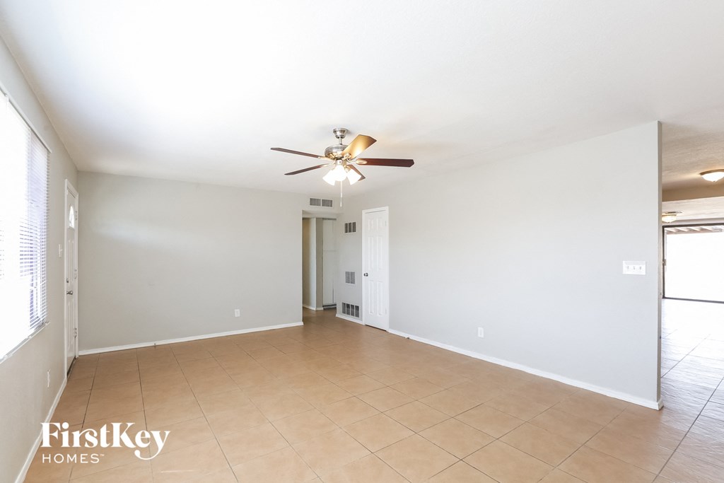 an empty living room with a ceiling fan and a tiled floor