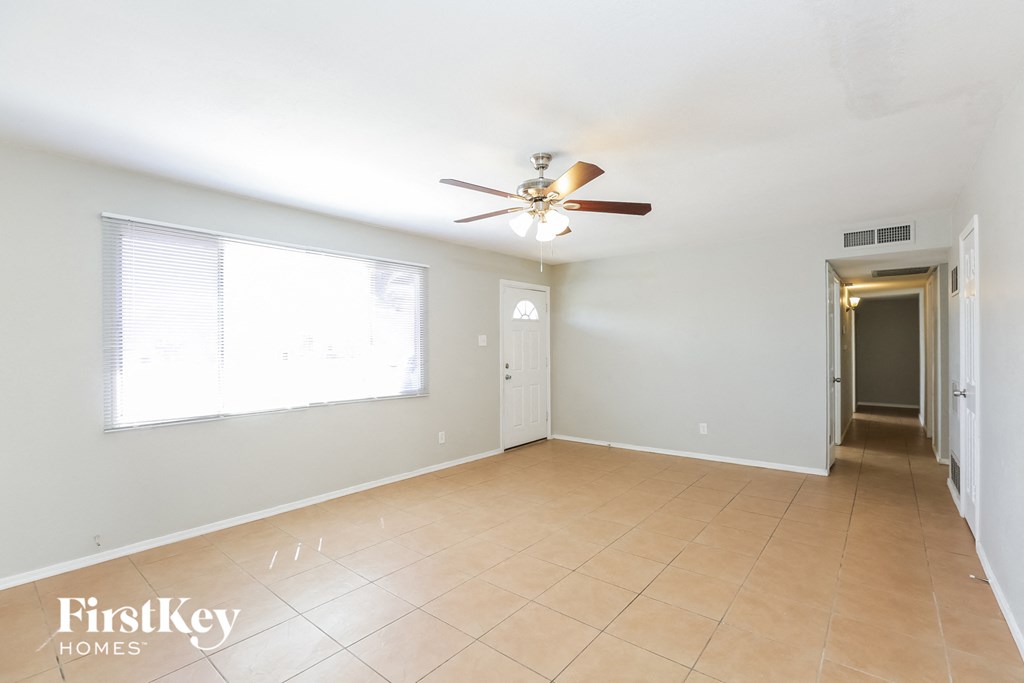 an empty living room with a ceiling fan and a large window