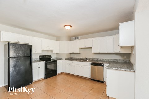 a kitchen with white cabinets and black appliances
