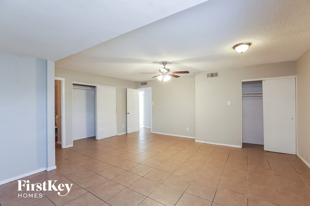 a spacious living room with tile flooring and a ceiling fan
