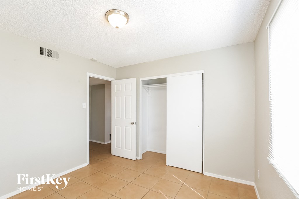a bedroom with a door to a closet and a tiled floor