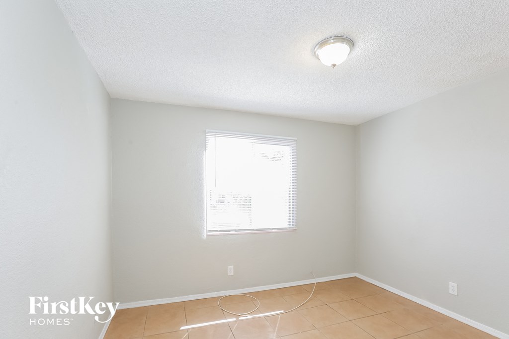 the living room of an empty house with a window and a tiled floor
