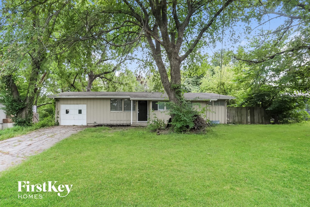 a small white house with a yard and trees