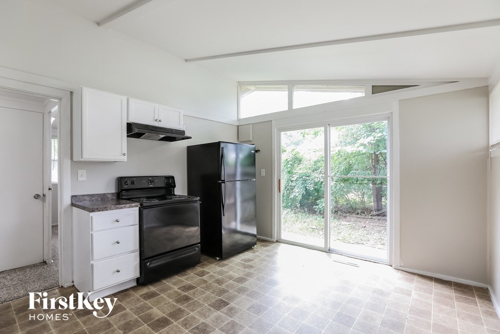an empty kitchen with black appliances and white cabinets and a sliding glass door