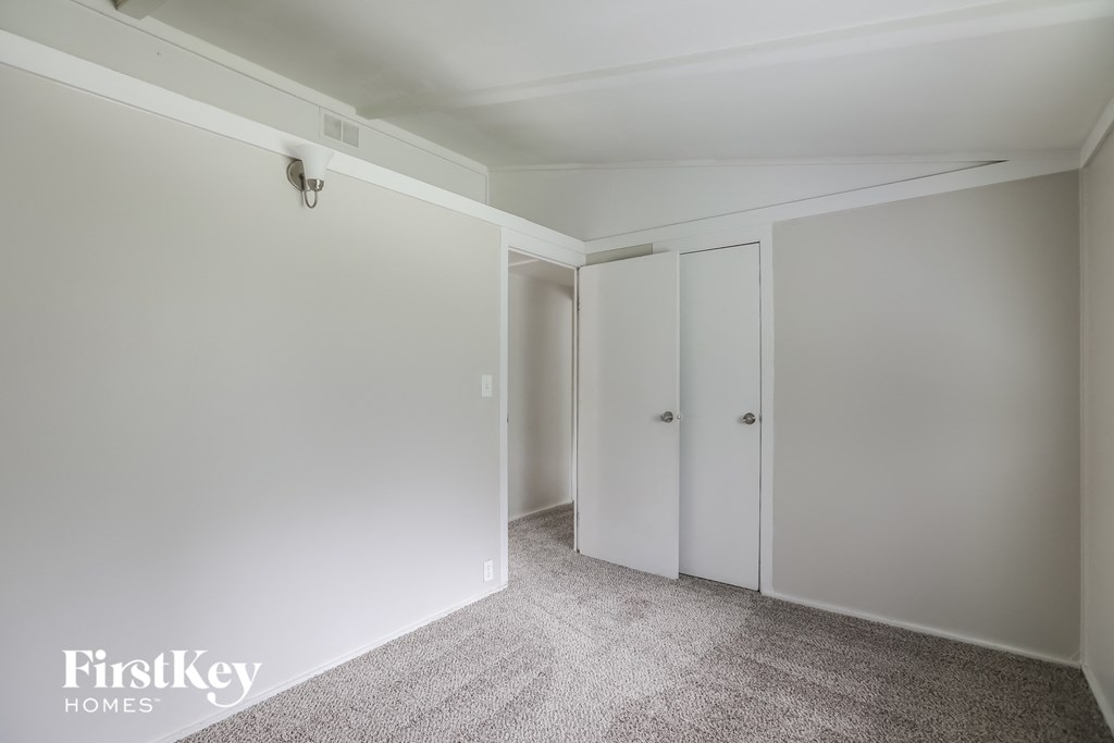 a bedroom with white walls and white closet doors