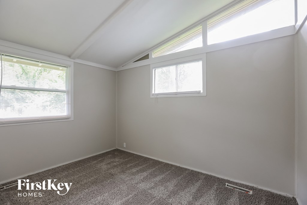 a small bedroom with two windows and a carpeted floor