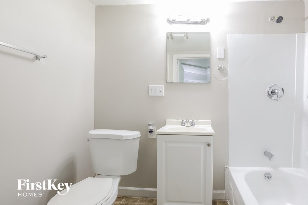 a white bathroom with a toilet sink and tub and a mirror