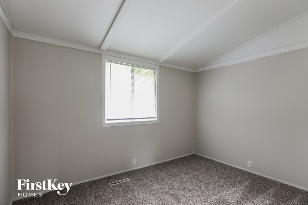 a bedroom with a window and a carpeted floor