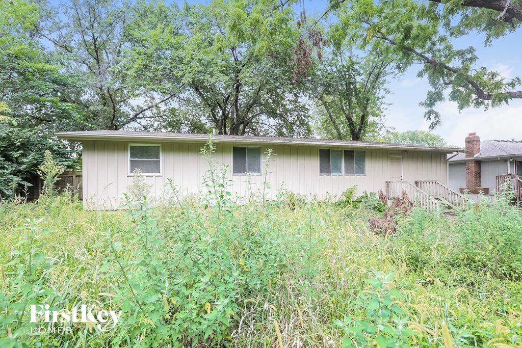 a small white house in a field of tall weeds