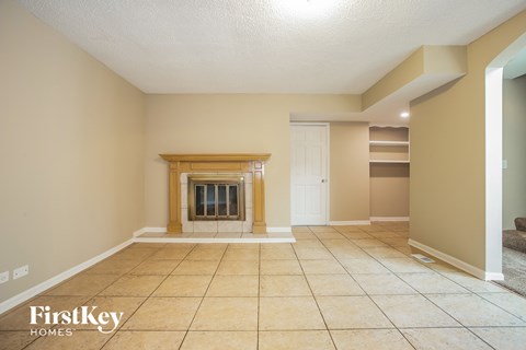 a large living room with a fireplace and tiled floors
