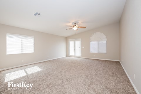 a spacious living room with carpet and a ceiling fan