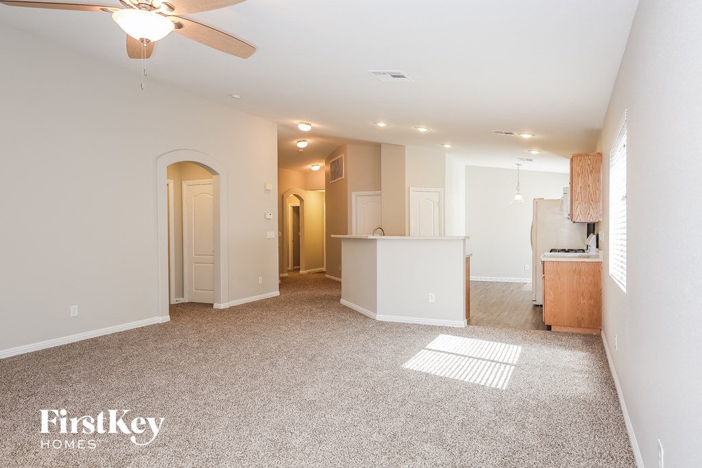 a living room with a kitchen and a ceiling fan