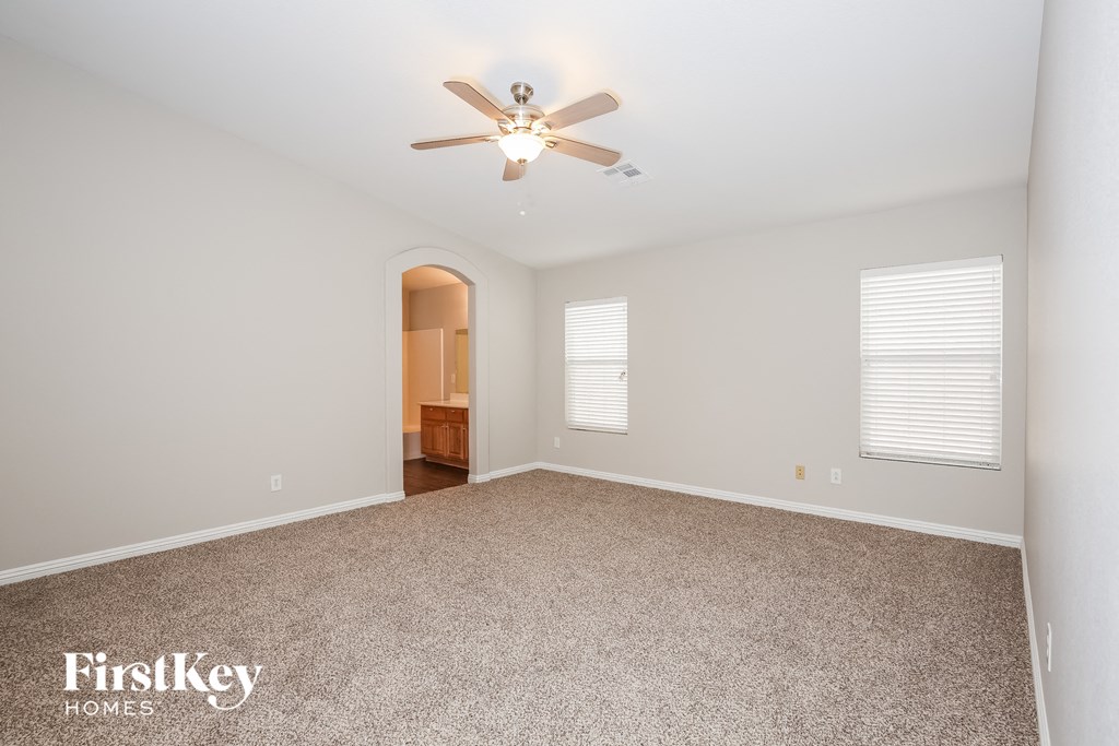 a spacious living room with carpet and a ceiling fan