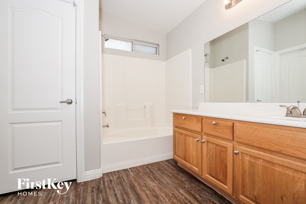 a bathroom with wooden cabinets and a tub and a sink