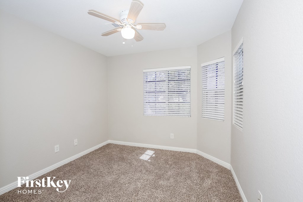 a spacious room with carpet and a ceiling fan