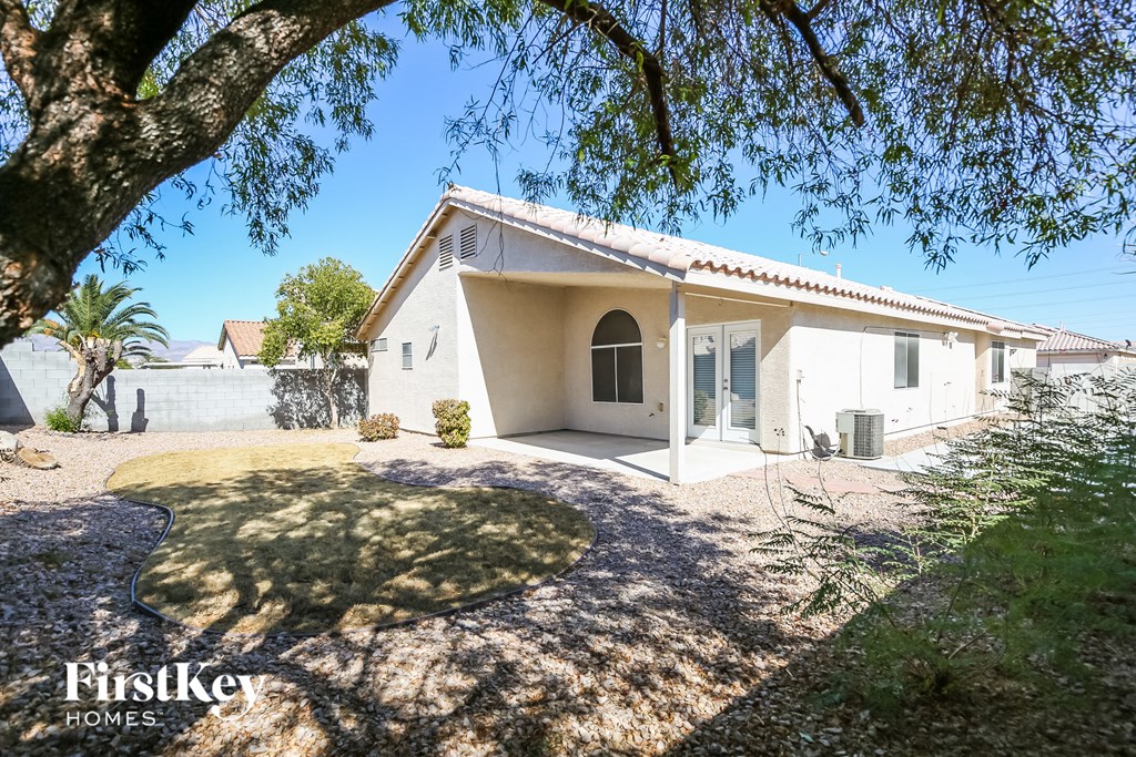 a small white house with a driveway and a tree
