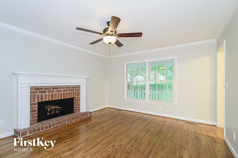 a living room with a brick fireplace and a ceiling fan