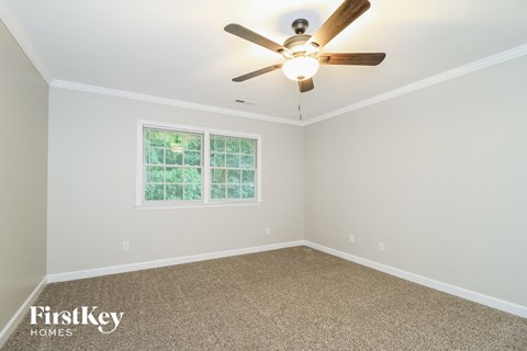 the master bedroom has a ceiling fan and a carpeted floor