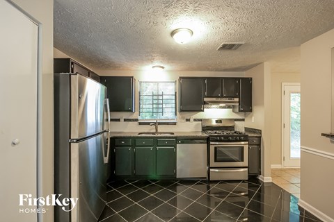 A kitchen with black cabinets and a black and white checkered floor.