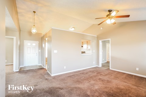 A spacious room with a carpeted floor and a ceiling fan.