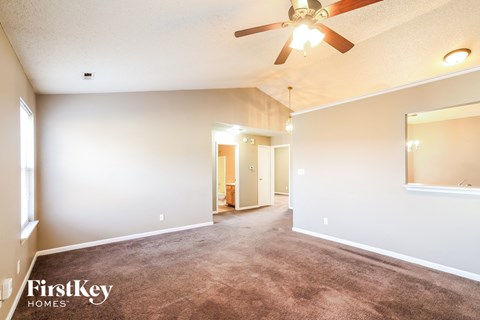 A spacious room with a ceiling fan and a carpeted floor.
