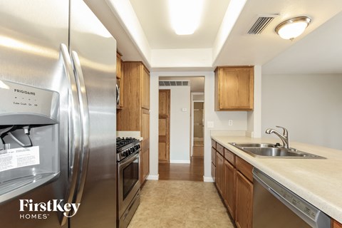 A kitchen with a stainless steel refrigerator and wooden cabinets.