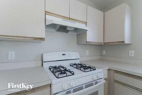 A white gas stove in a kitchen with beige cabinets.
