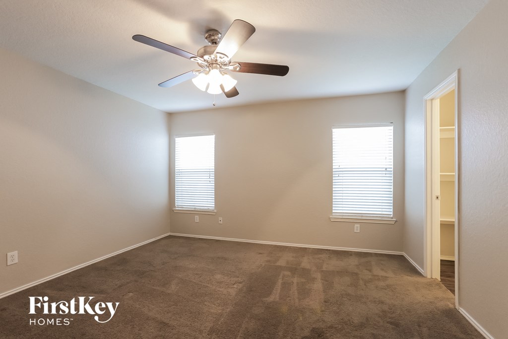 a empty living room with a ceiling fan and a window