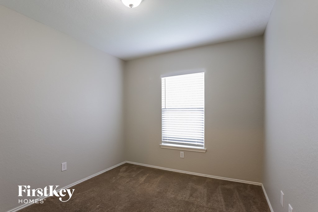 a bedroom with a window and a carpeted floor