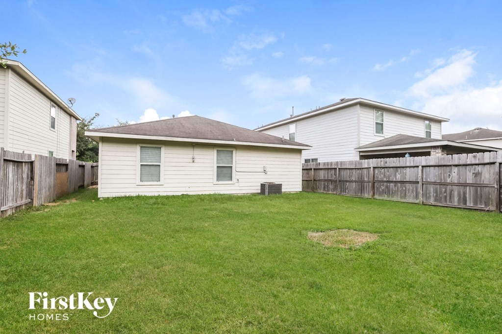 a backyard with a white house and a wooden fence