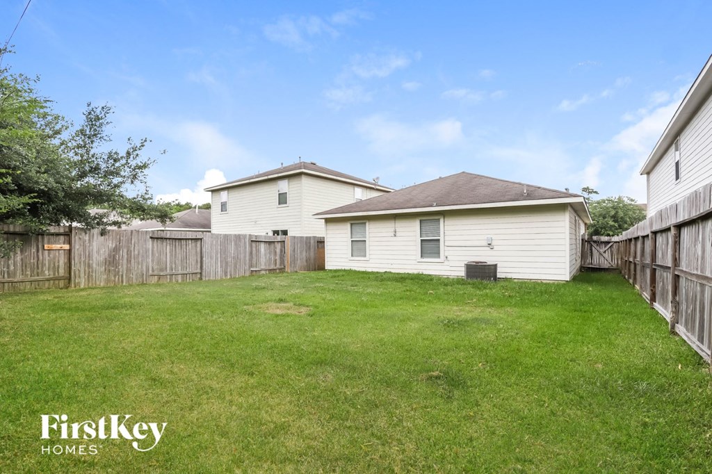 a backyard with a white house and a wooden fence