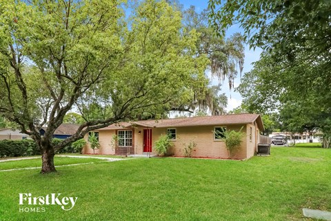 a small pink house with a yard and trees