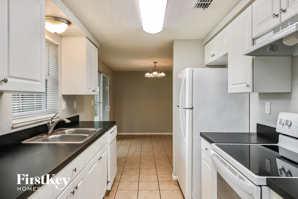 a kitchen with white cabinets and black counters and a white refrigerator