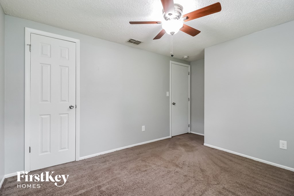 the spacious living room with carpeting and a ceiling fan