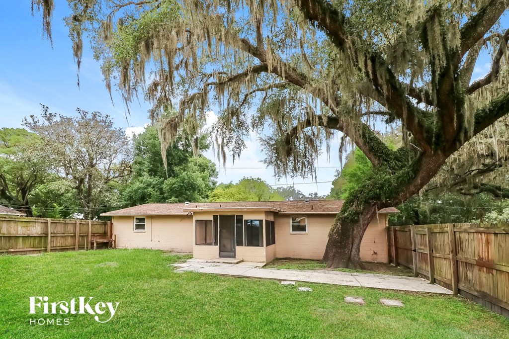 a small tan house with a tree and a fence