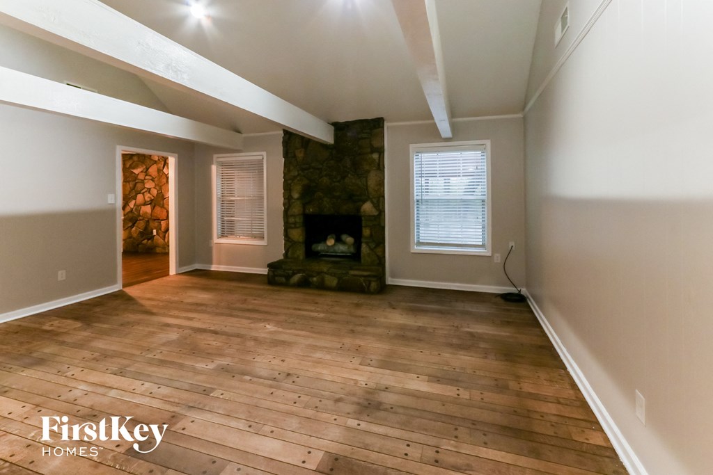 A room with wooden floors and a fireplace is shown.