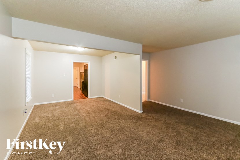 A carpeted room with a doorway leading to another room.