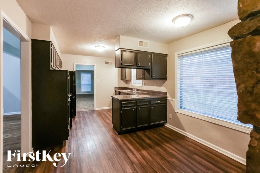 A kitchen with a black fridge and cabinets.