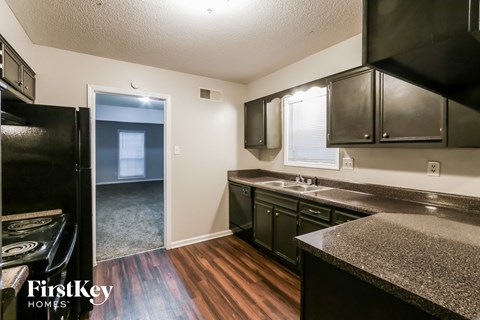 A kitchen with black cabinets and a granite countertop.