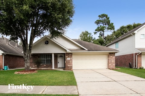 a white and brick house with a driveway and a tree