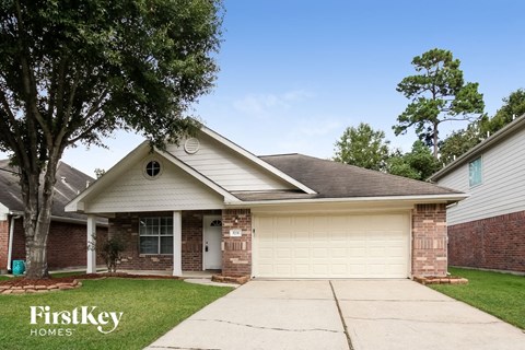 a white and brick house with a driveway and a tree