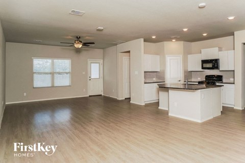 an open kitchen and living room with white cabinets and a wood floor