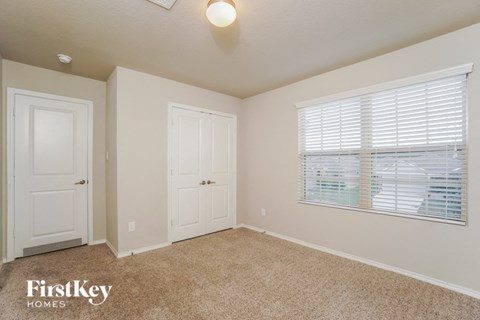 a bedroom with beige carpet and a window and white doors